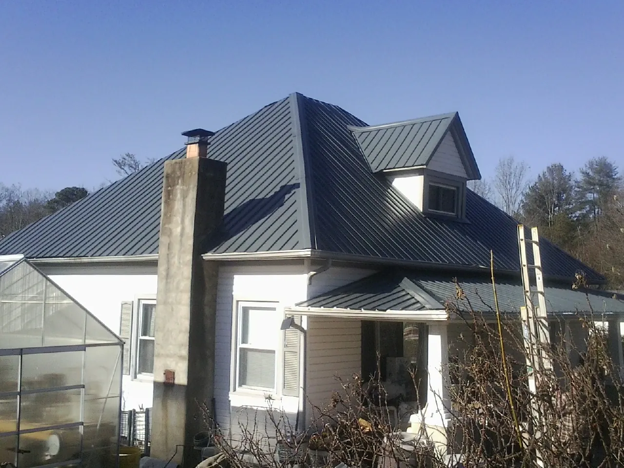 Dark blue standing seam metal roof on a white farmhouse with dormer — Slate & Tile Roof Repair by Roofing Brothers in Oconomowoc