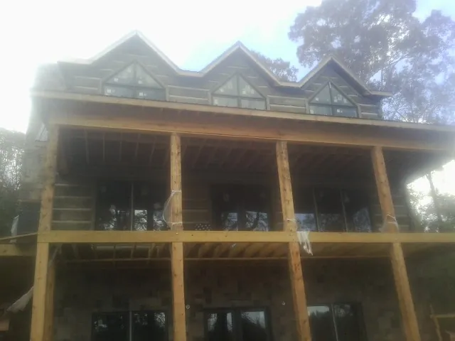 Dormers and porch framing on a large log home under construction — Roof Coating work by our crew in Oconomowoc