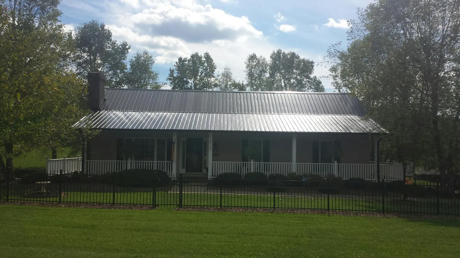 Gray metal roof on a brick ranch with a full width front porch — Gutter Guard Installation work by our crew in Oconomowoc
