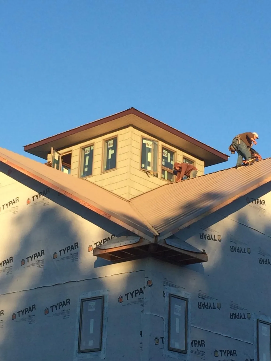 Roofers working around a rooftop cupola on a new metal roof at sunset — Roof Waterproofing in Oconomowoc by Roofing Brothers